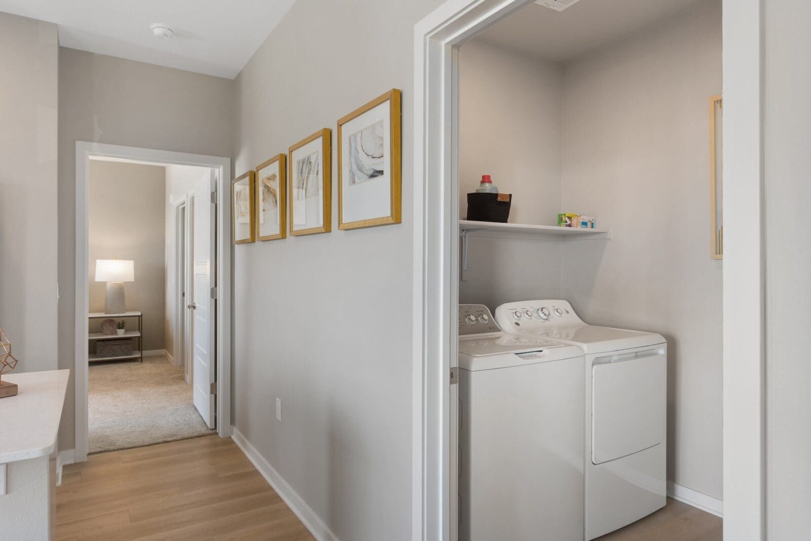 Hallway with laundry room on right, bedroom in distance, framed art on wall at Echo Biltmore in Phoenix, AZ..