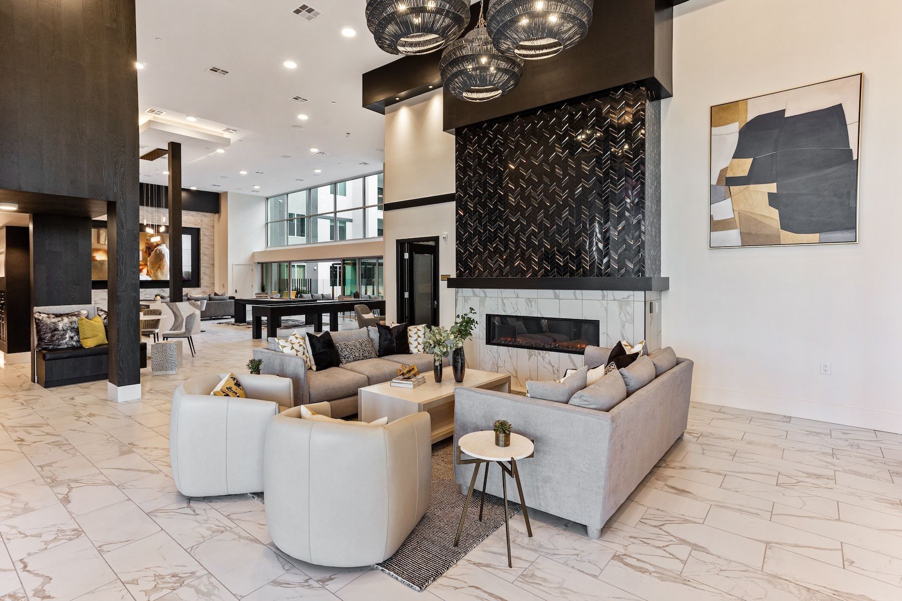 Upscale lobby with fireplace, sofas, and pool table. Modern design, marble floors, and decorative lights at Echo Biltmore in Phoenix, AZ..
