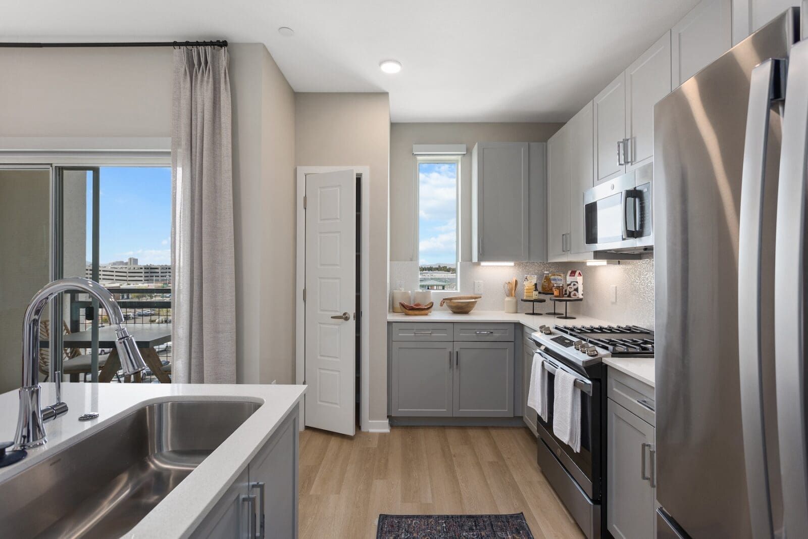 Modern kitchen with gray cabinets, stainless steel appliances, and a balcony view at Echo Biltmore in Phoenix, AZ..