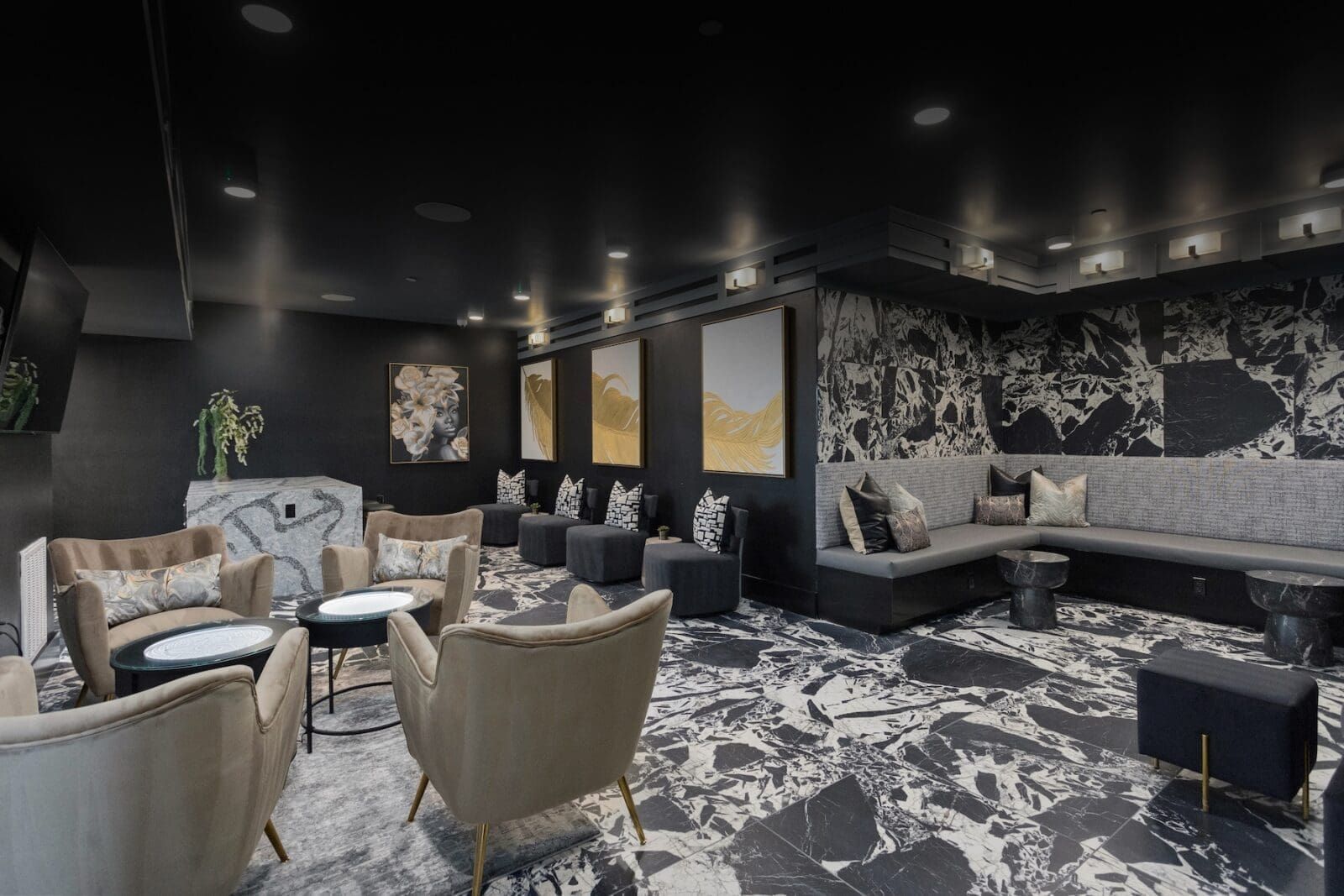 A modern lounge with dark walls, patterned floor, seating areas, artwork, and a marble-topped bar at Echo Biltmore in Phoenix, AZ..