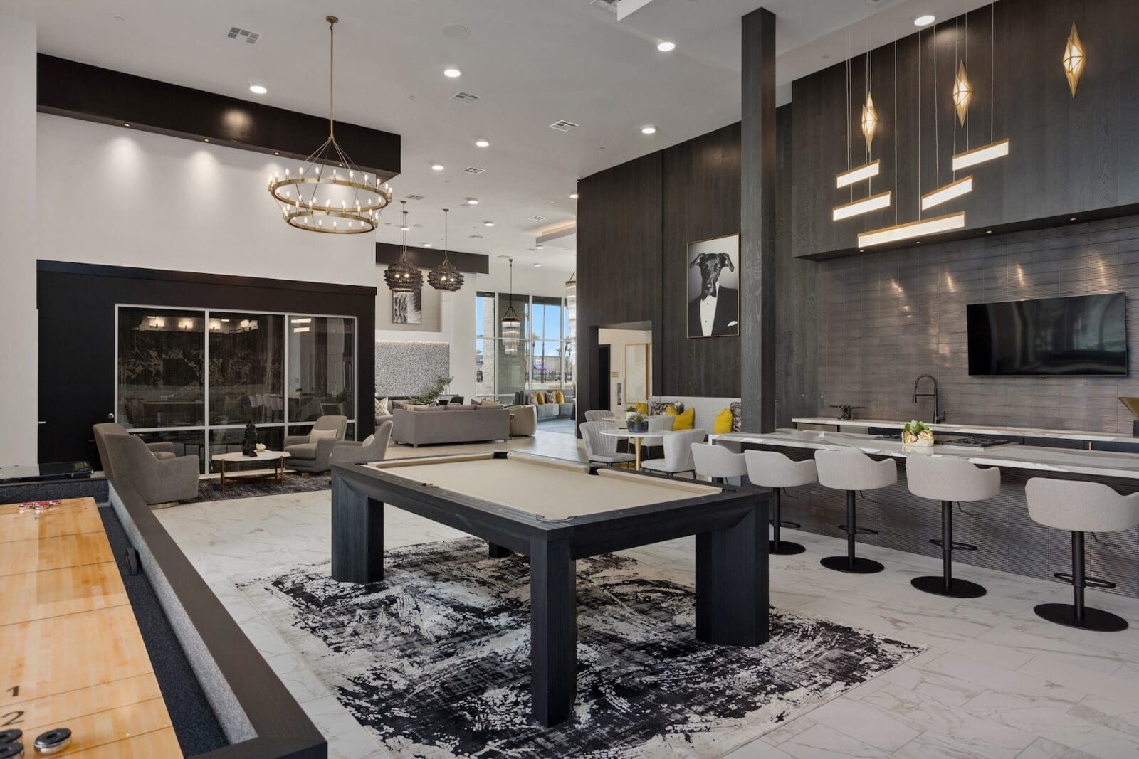 Modern lounge with pool table, seating area, bar with stools, and hanging lights.