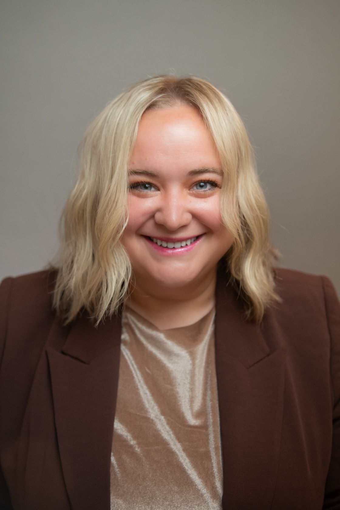 Woman with blonde wavy hair, smiling, indoors.
