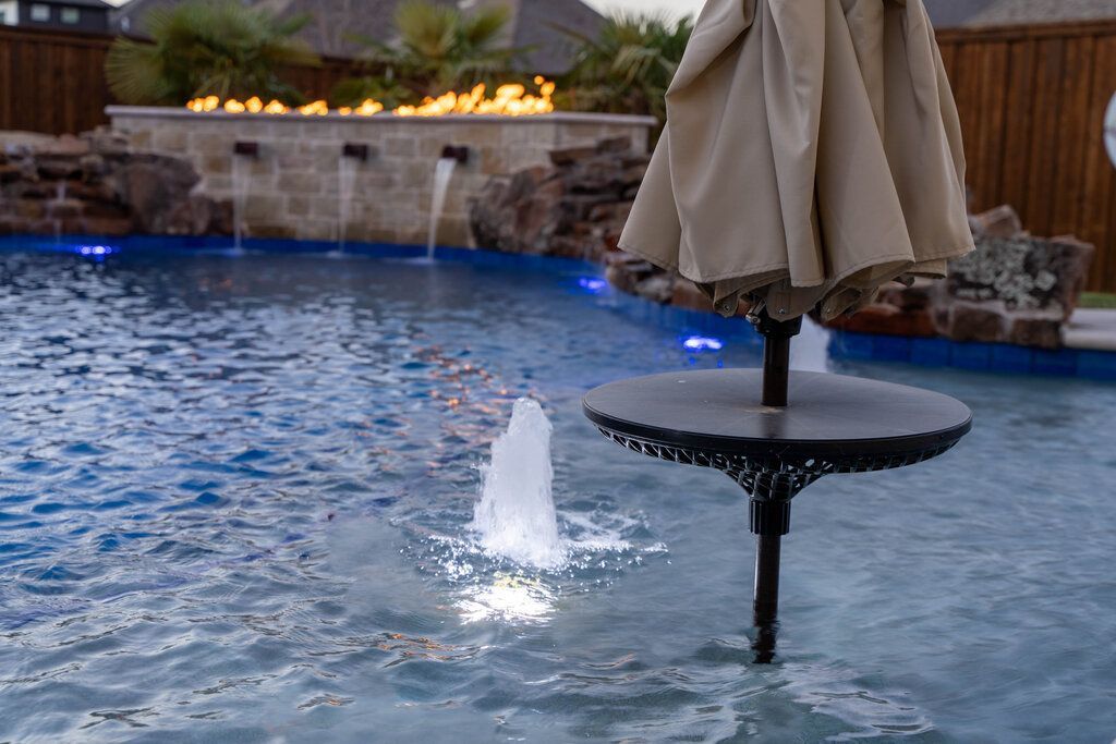umbrella and table in middle of pool with fountain