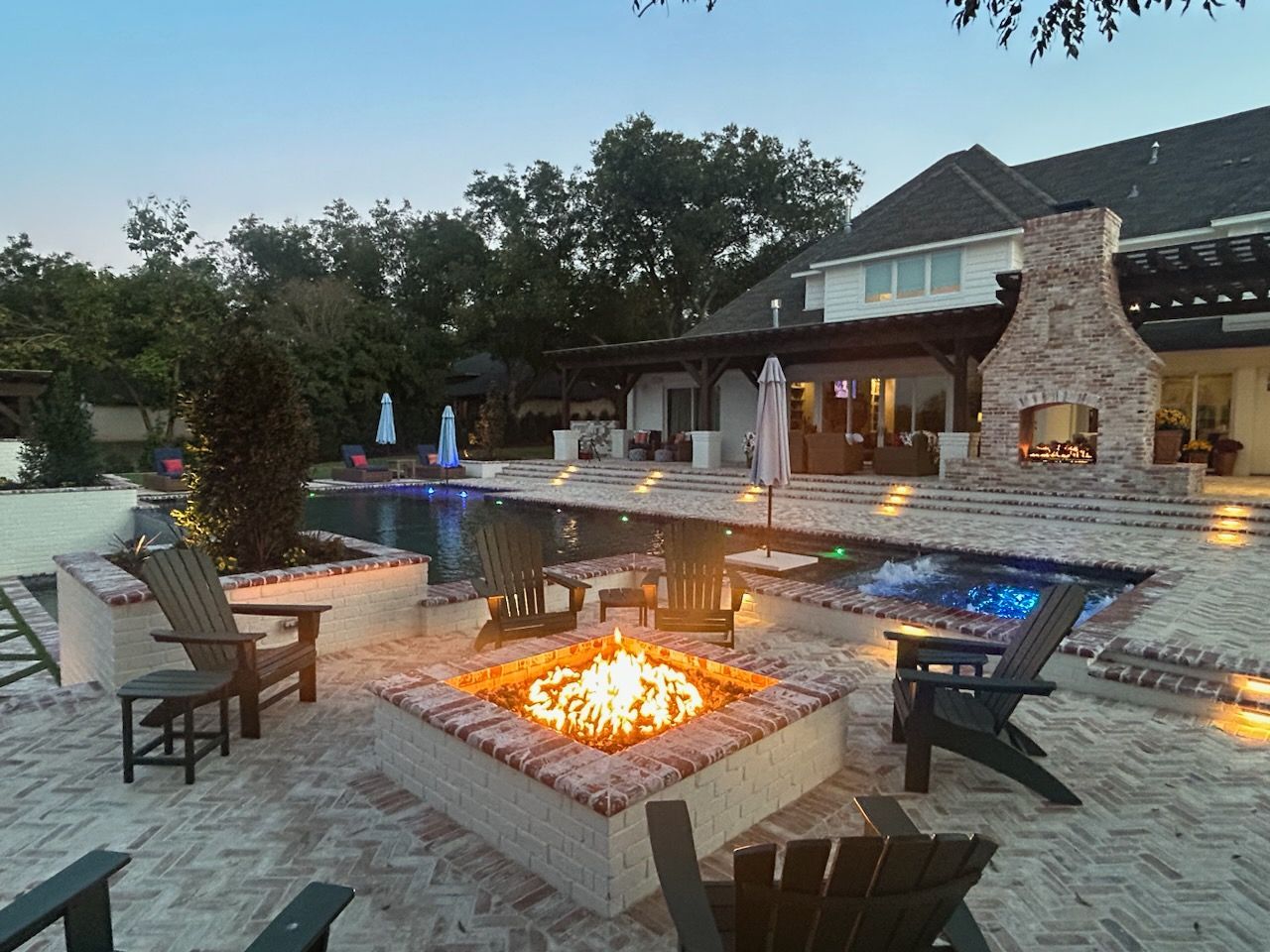 Backyard with pool, fire pit, fireplace, and chairs. 