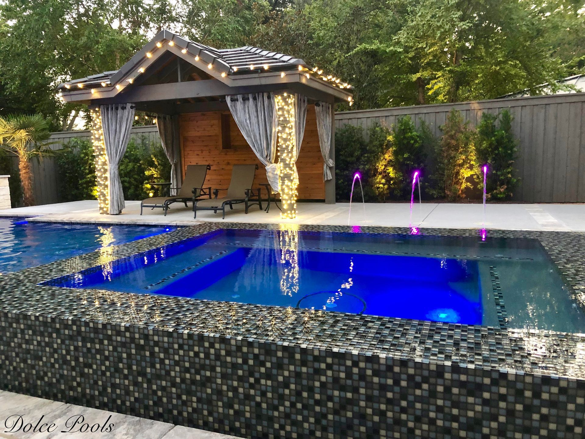 luxury pool with spout fountains and blue lights at night