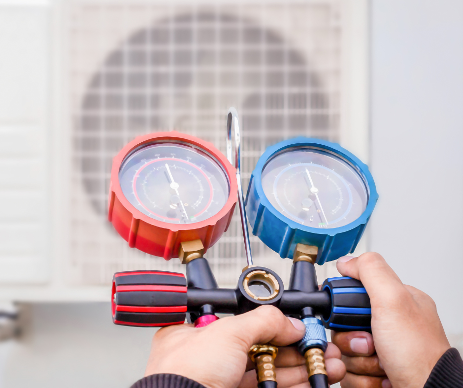 A person is holding a pressure gauge in front of an air conditioner.