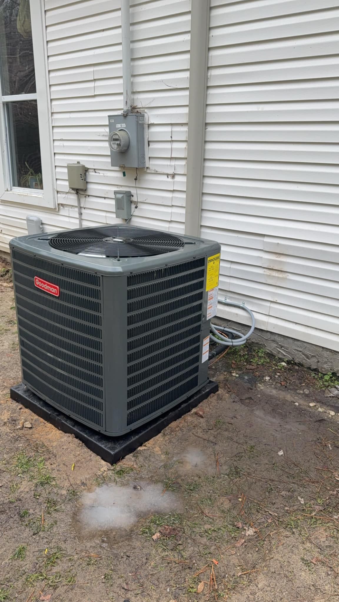 A large air conditioner is sitting on the side of a house.