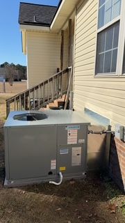 A large air conditioner is sitting on the side of a house.