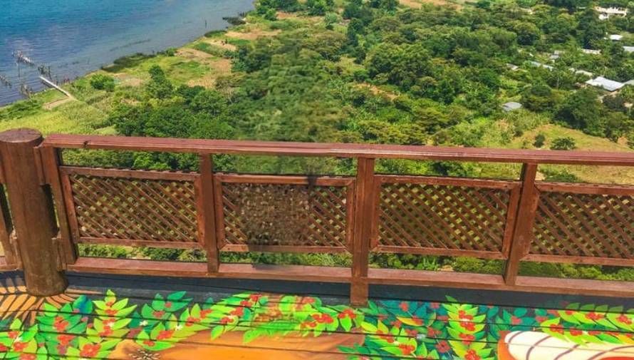 Una barandilla de madera con vista a un cuerpo de agua y un exuberante bosque verde.