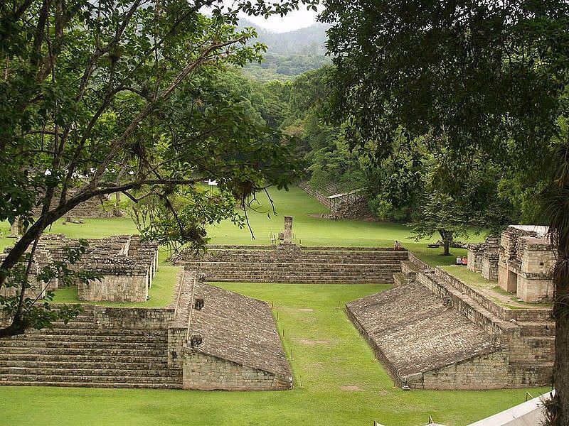 Un gran edificio de piedra con escaleras rodeado de césped y árboles.