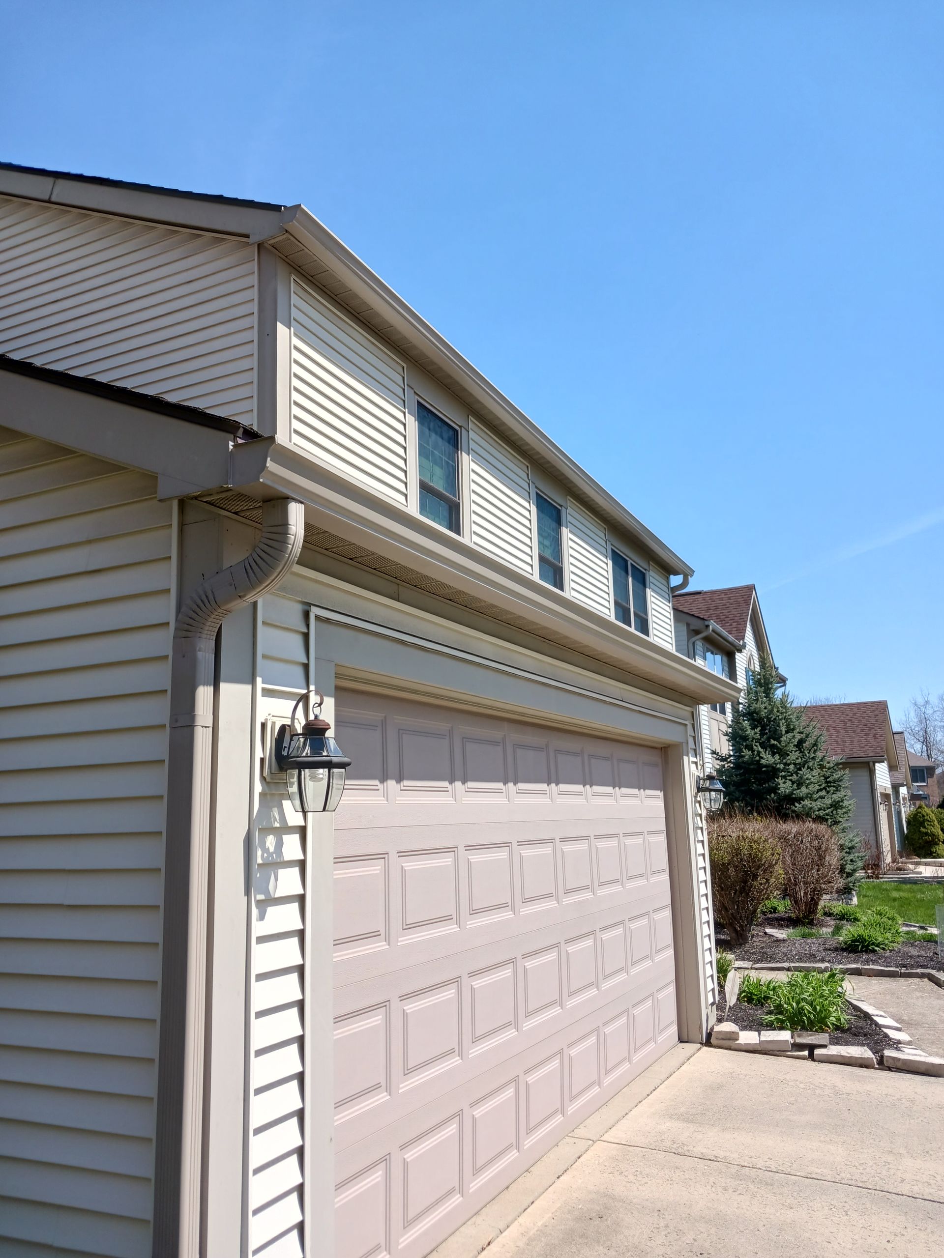 Beige house with a tan garage door under a blue sky.