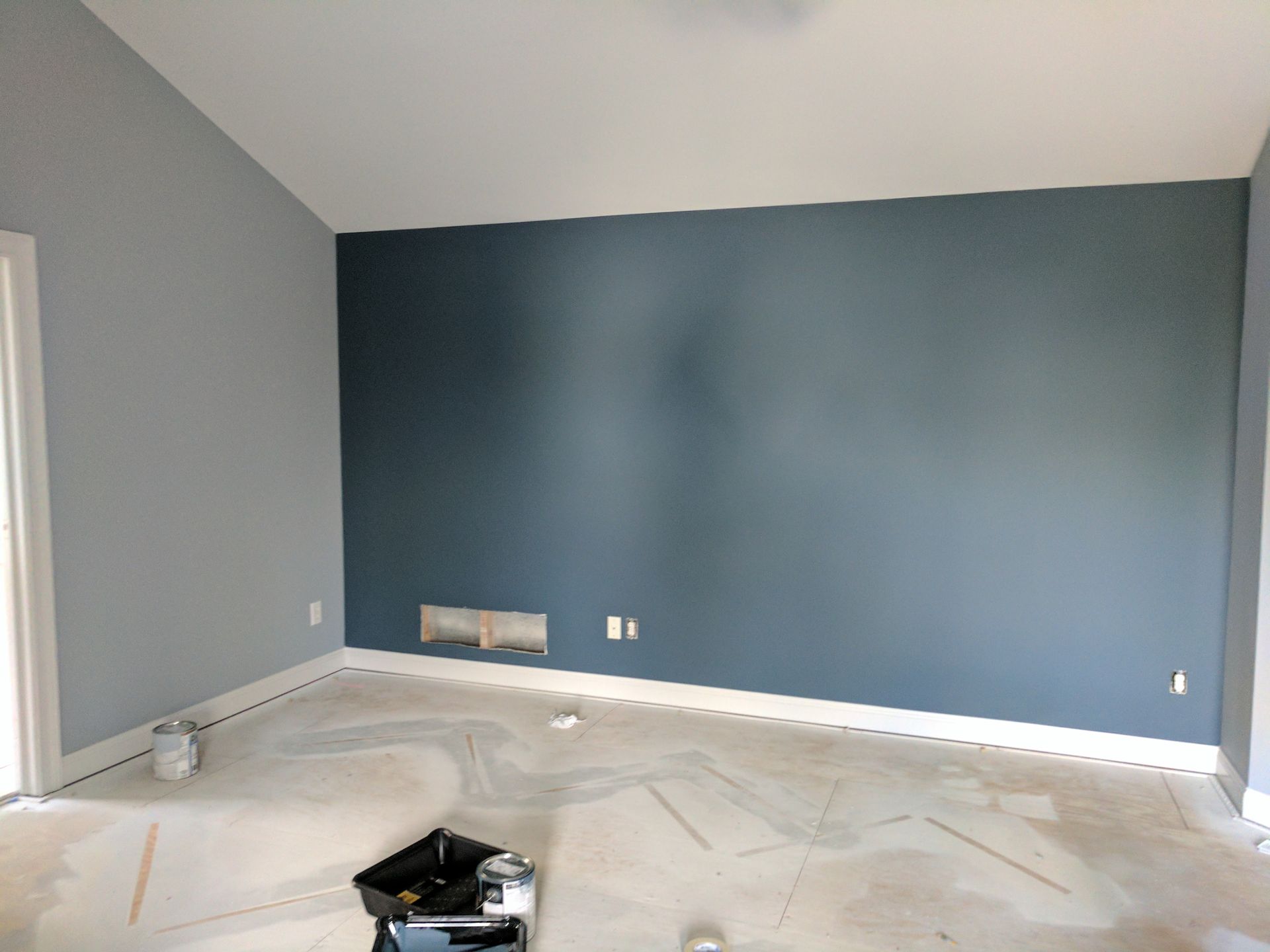 Empty room with blue-gray and dark blue walls, white trim, and concrete floor.