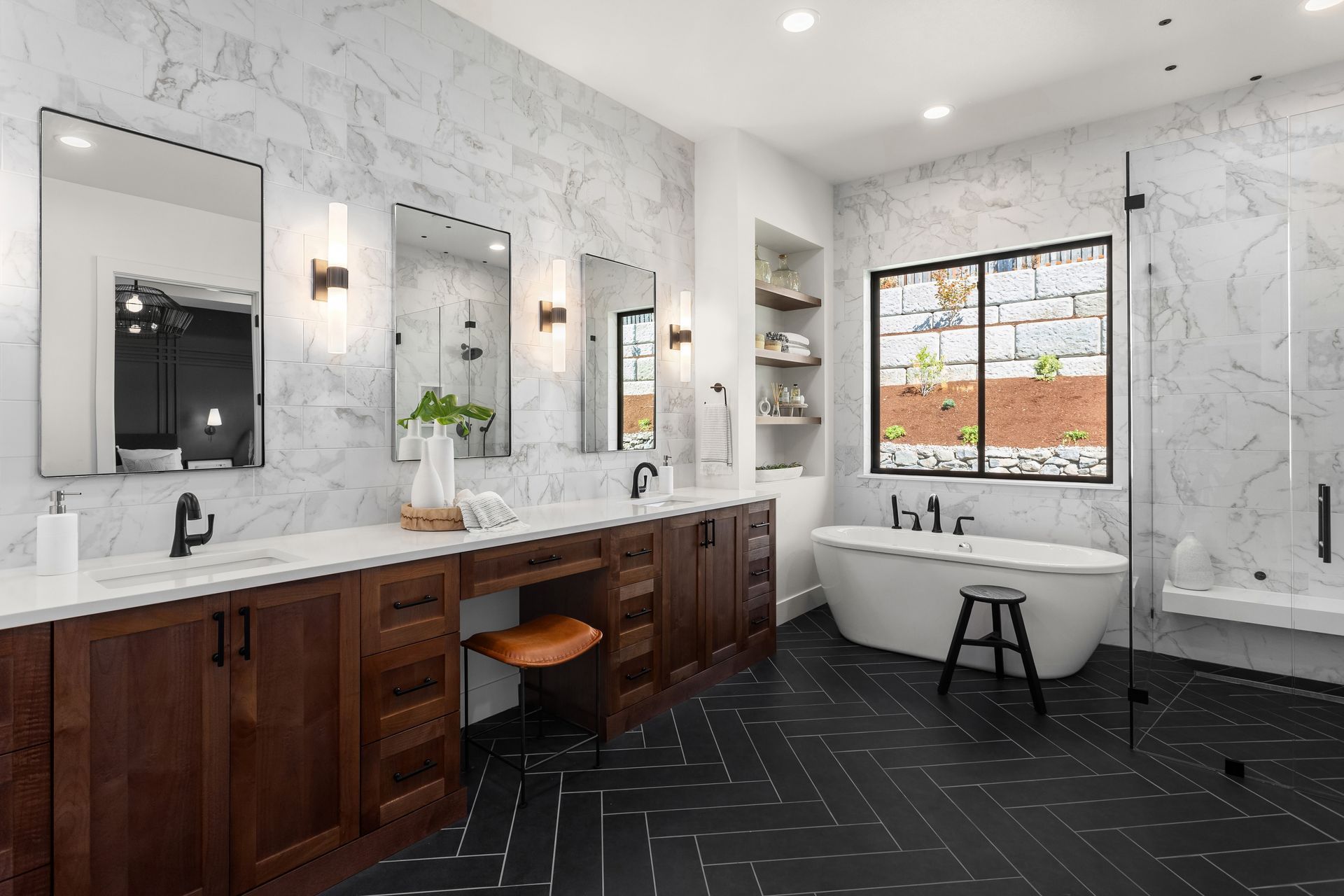 Spacious modern bathroom with dark wood vanity, white marble walls, and a soaking tub.