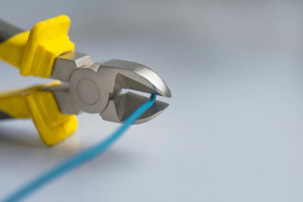 A pair of pliers is cutting a blue wire