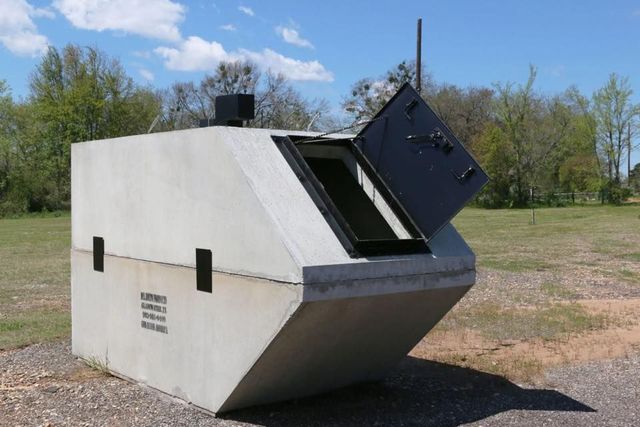 Large concrete bunker or utility structure outdoors with an open black hatch lid