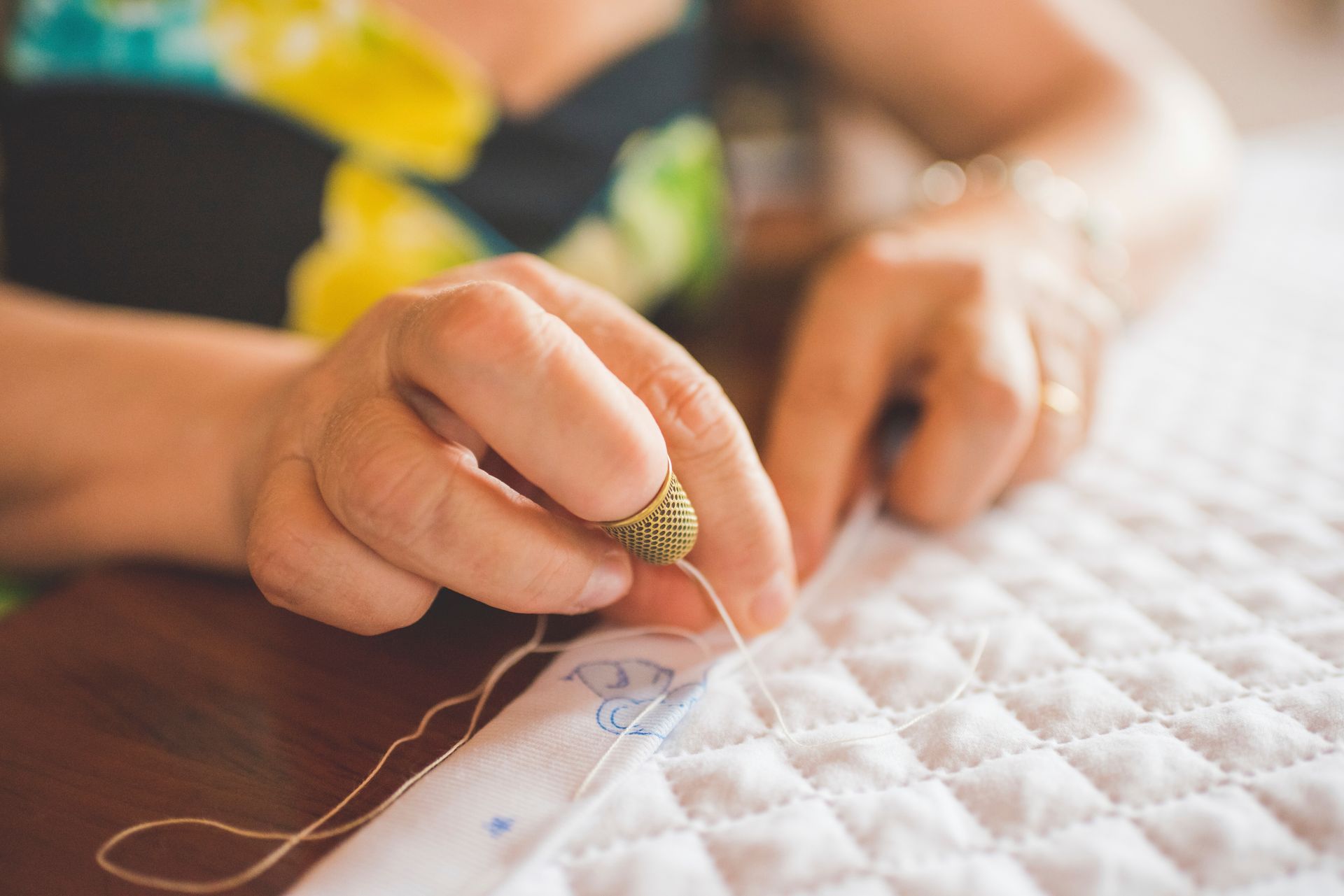 Close-up of woman sewing the hem on a quilt
