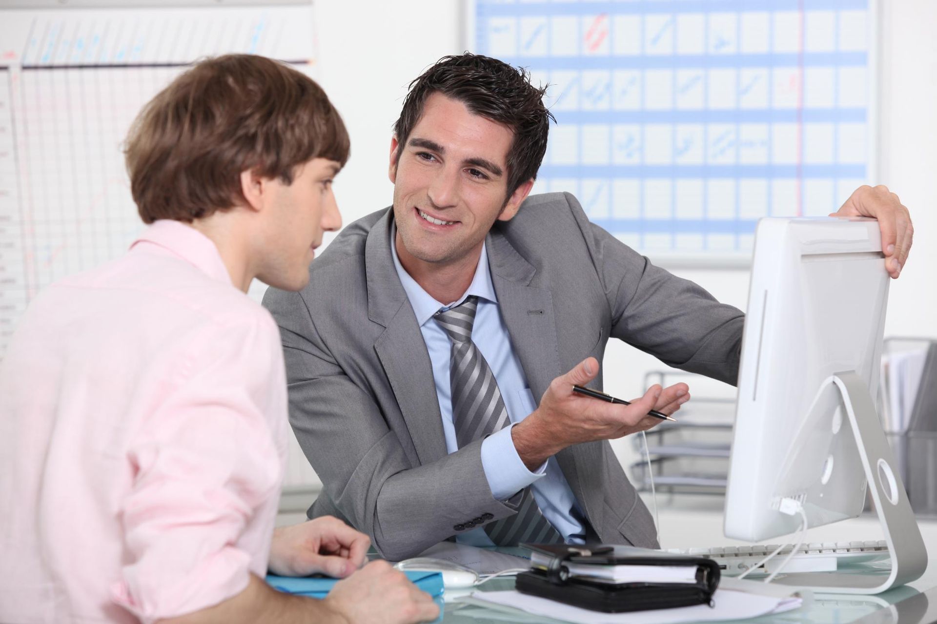 Two men are looking at a computer screen and smiling