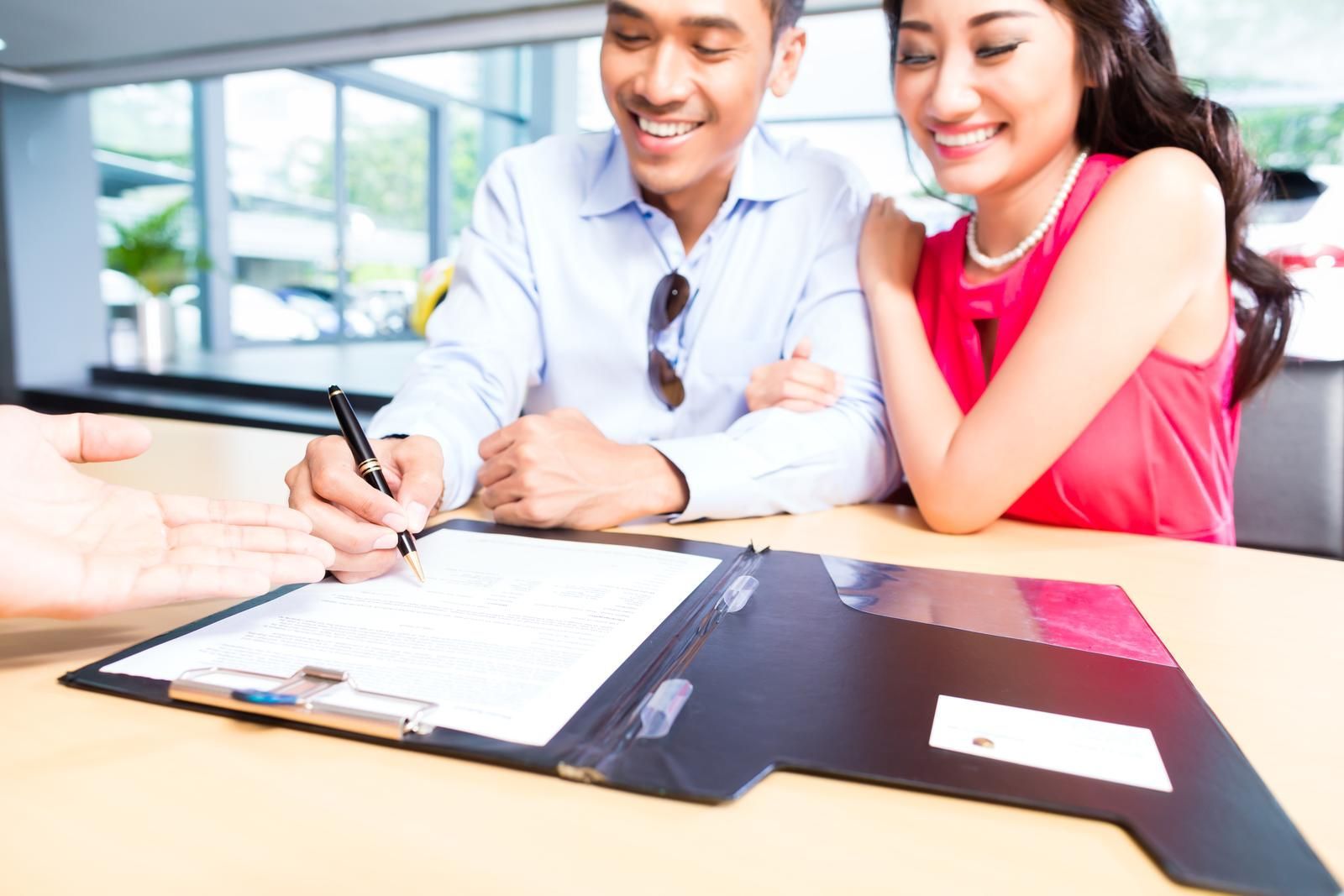 A man and a woman are signing a document on a clipboard