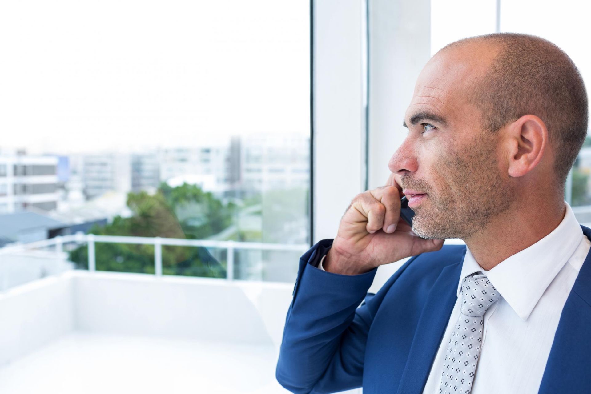 A man in a suit and tie is looking out a window