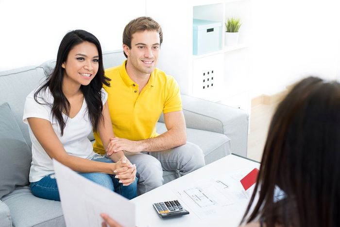 A man and woman are sitting on a couch talking to a woman