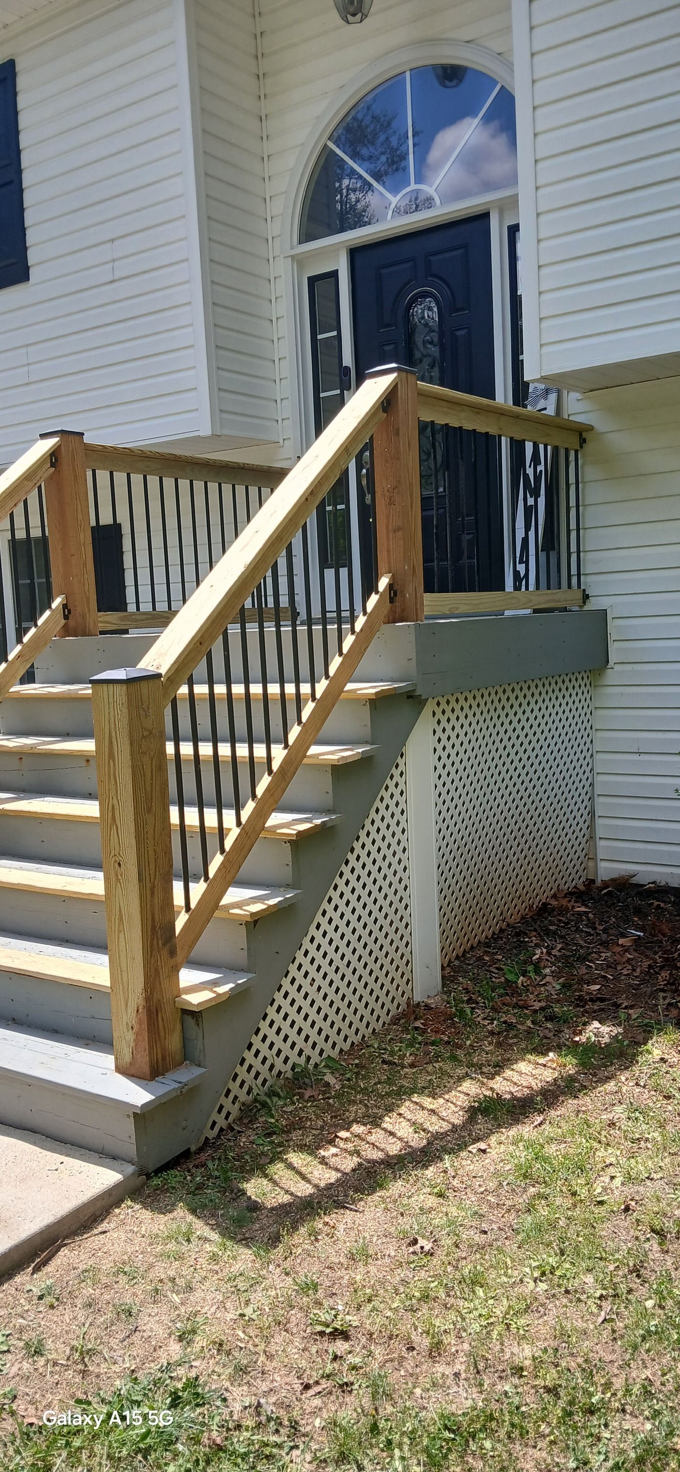 Two people working on a room renovation, one installing drywall on a wall from a wooden ladder, under bright light.