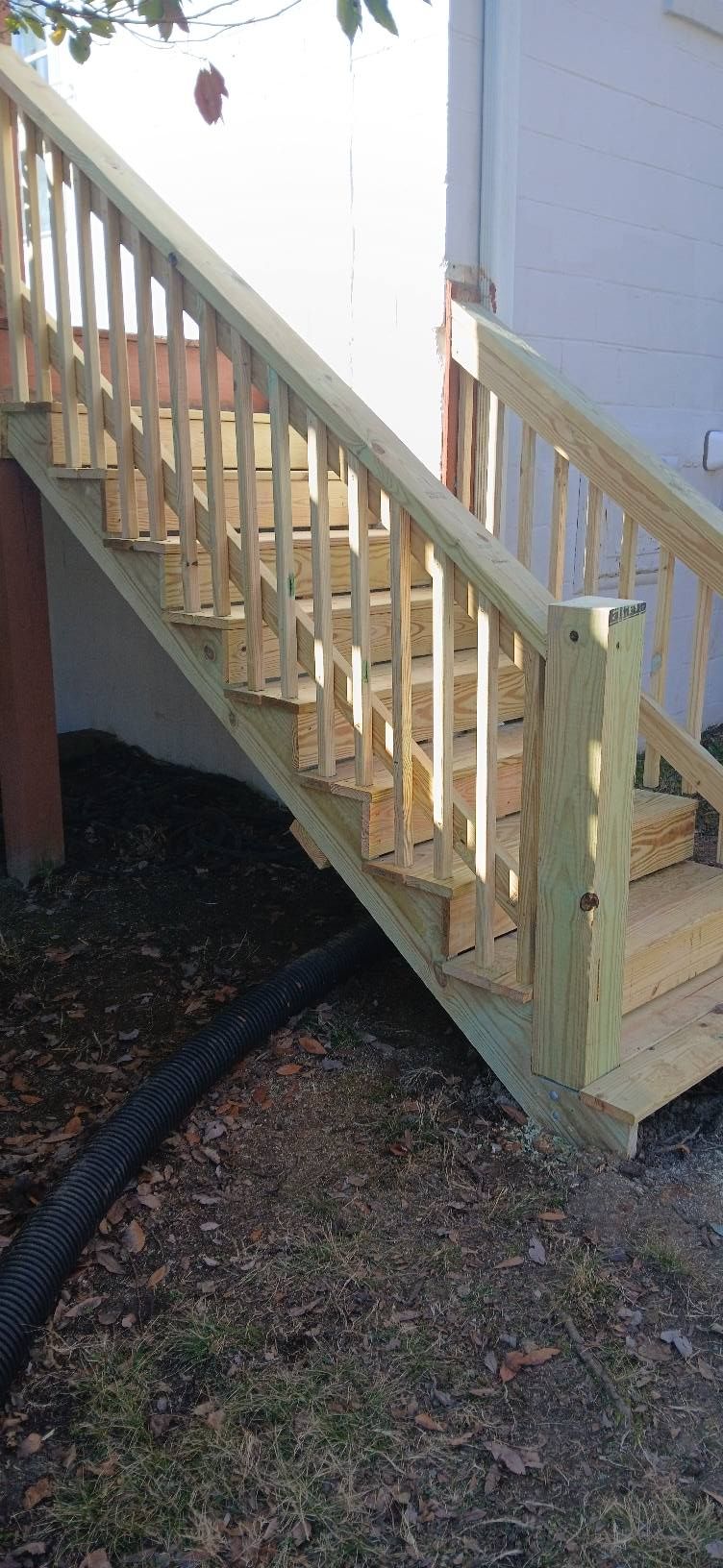 A modern outdoor patio featuring a gray sofa and armchairs, a wooden privacy fence, a glass roof, and a covered grill.