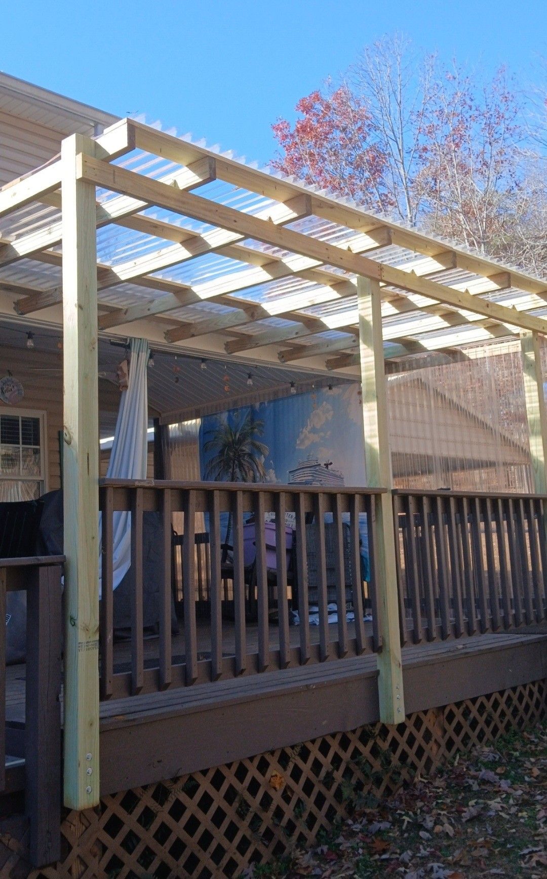 A person's gloved hand uses a nail gun to attach a shingle to a residential roof.
