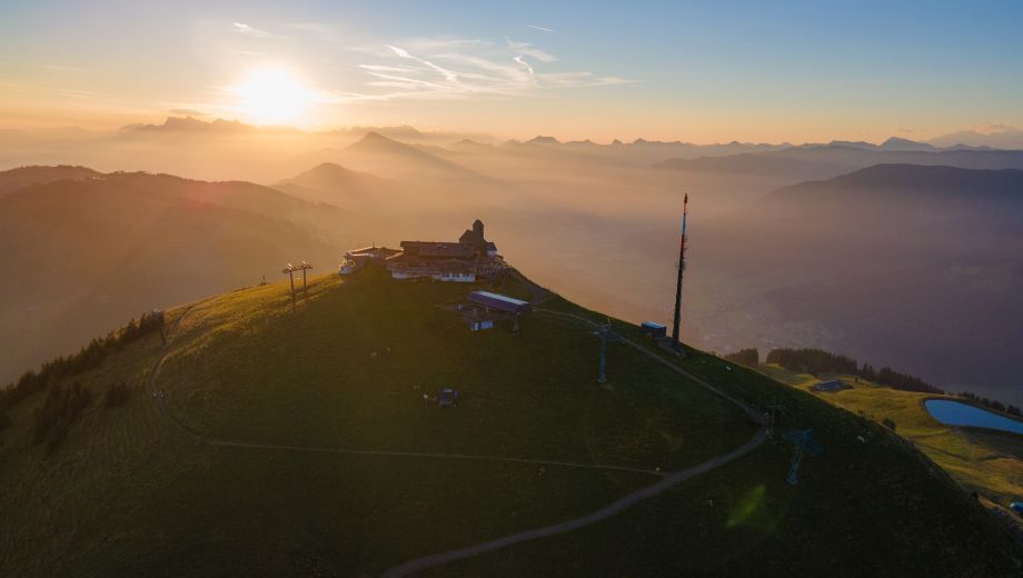 An aerial view of a house on top of a mountain at sunset.