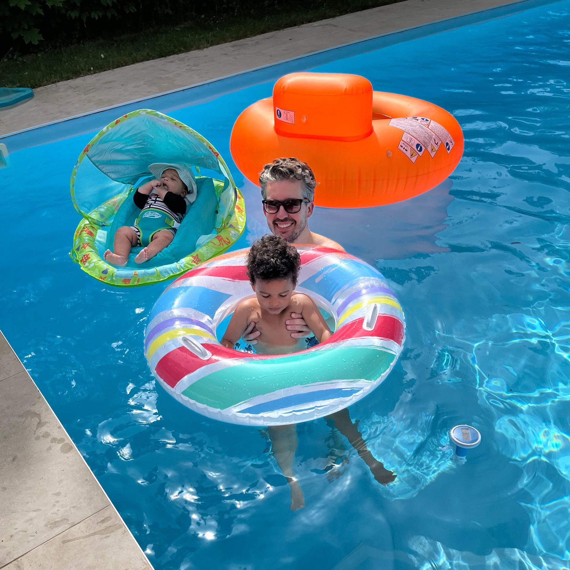 A photo of Oliver swimming with his two children. 
