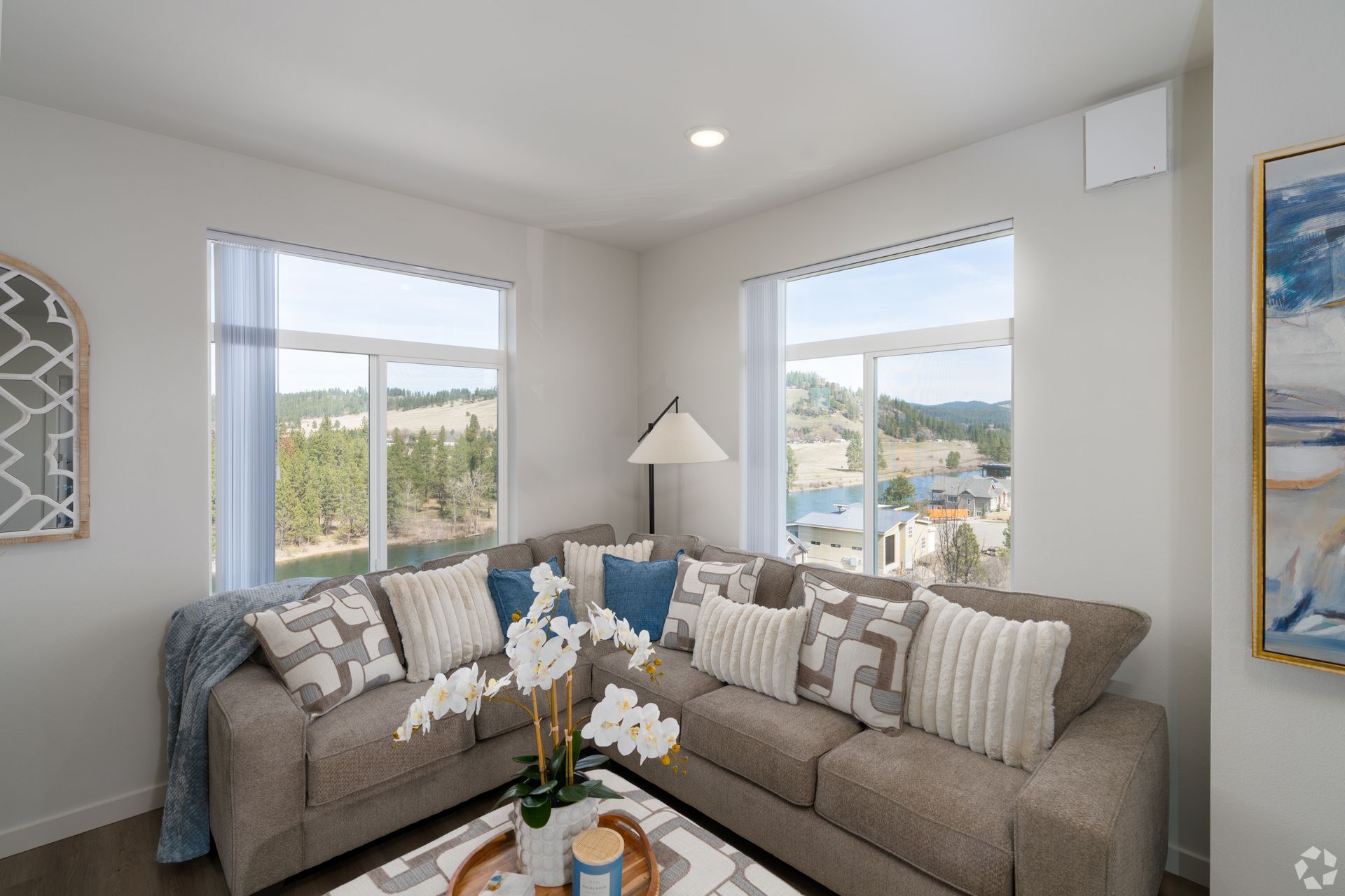 A living room with a couch , table , and two windows.