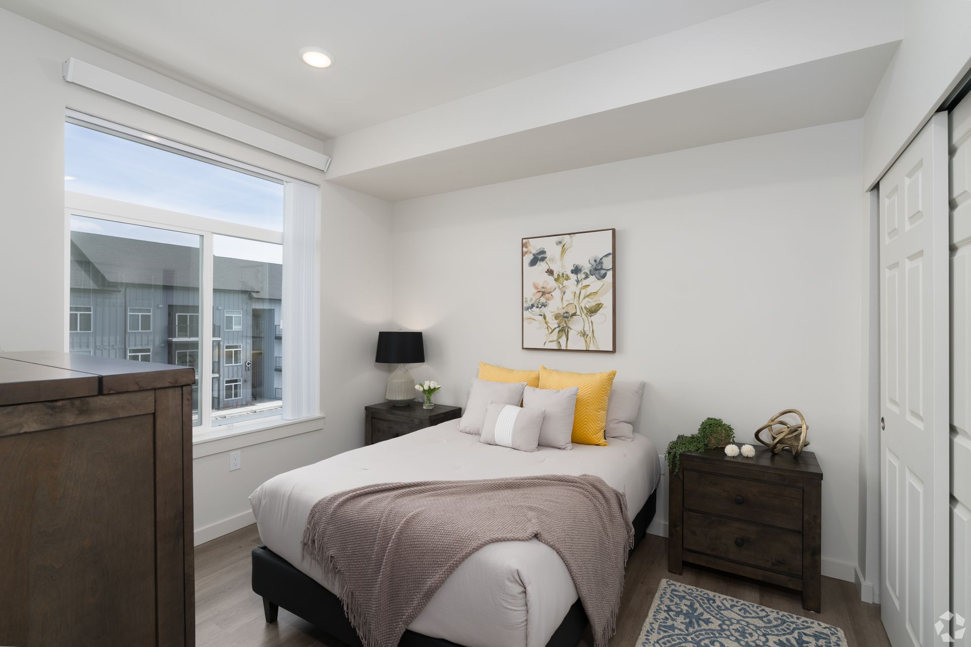 A bedroom with a bed , nightstand , dresser and window.