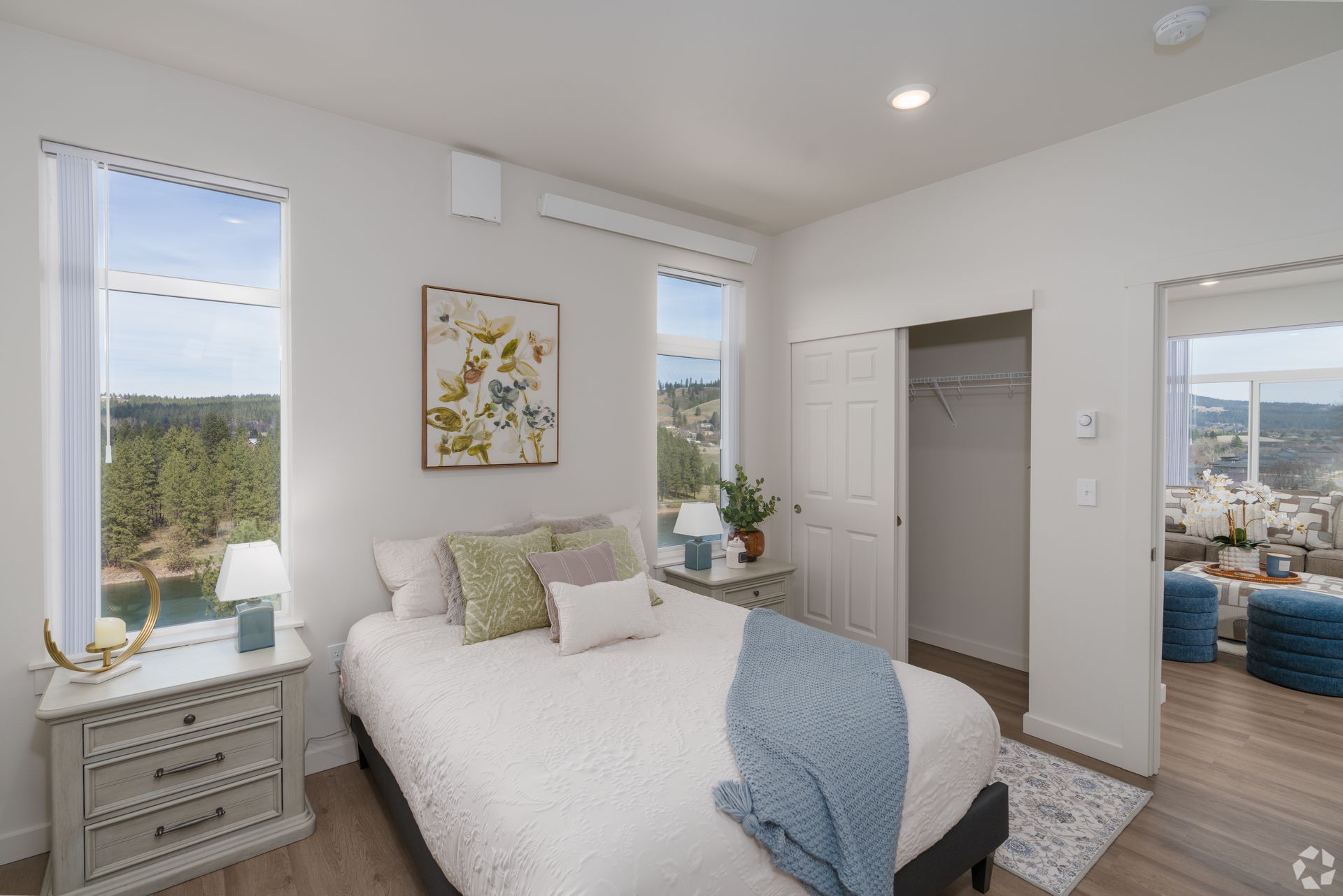 A bedroom with a bed , nightstand , and two windows.