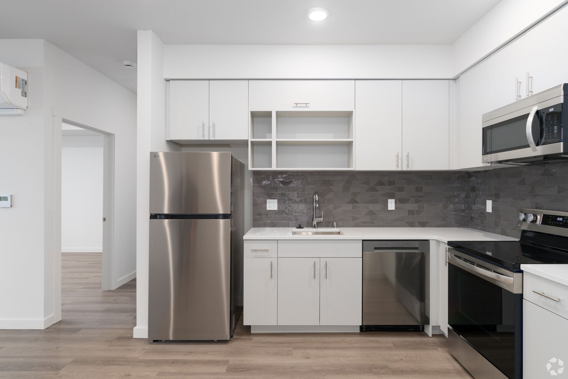 A kitchen with stainless steel appliances and white cabinets.