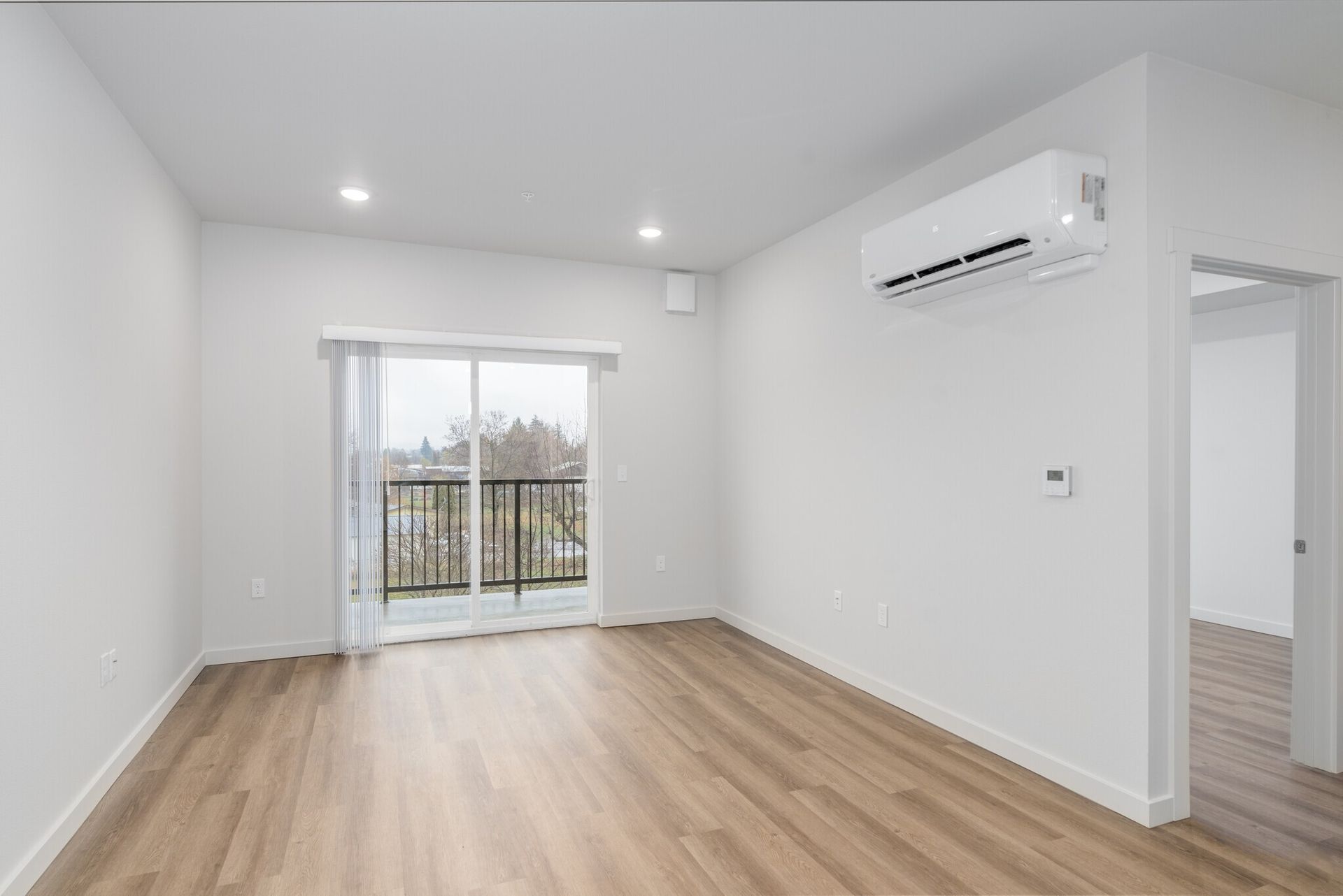 An empty living room with hardwood floors and a balcony.