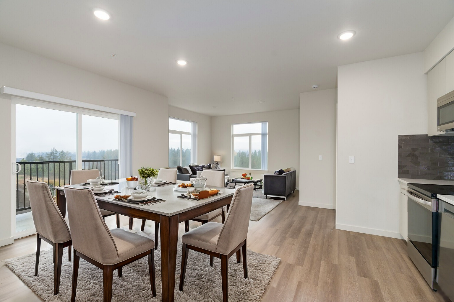 A living room with a dining table and chairs and a kitchen.