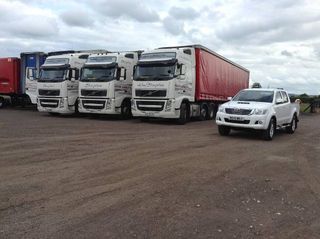 A car parked next to three lorries