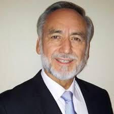A man with a beard is wearing a suit and tie and smiling.