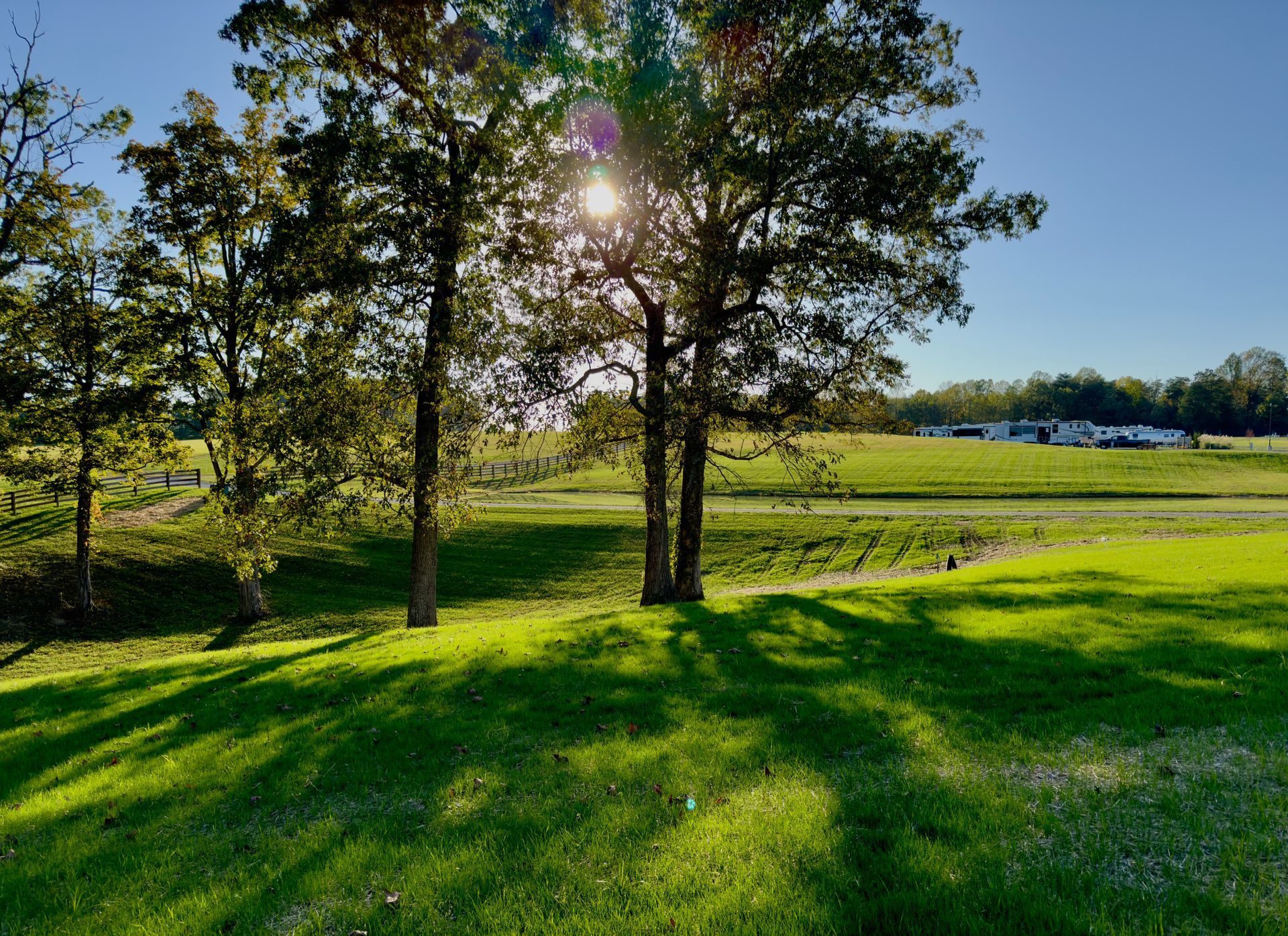 An orange tent is sitting on top of a grassy hill next to a body of water.