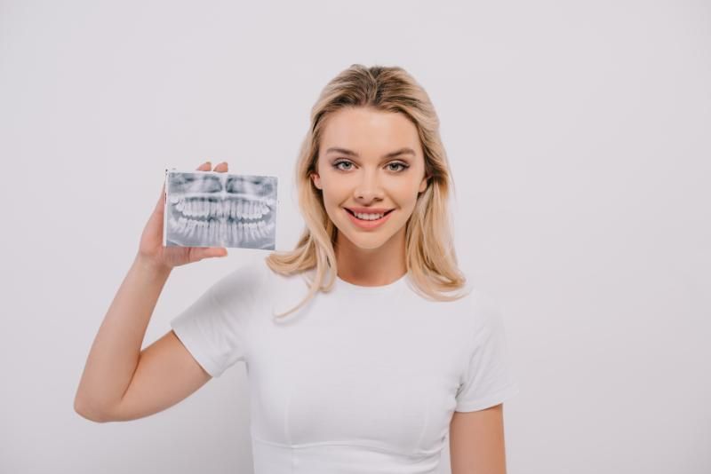 A woman is holding a picture of her teeth in front of her face.