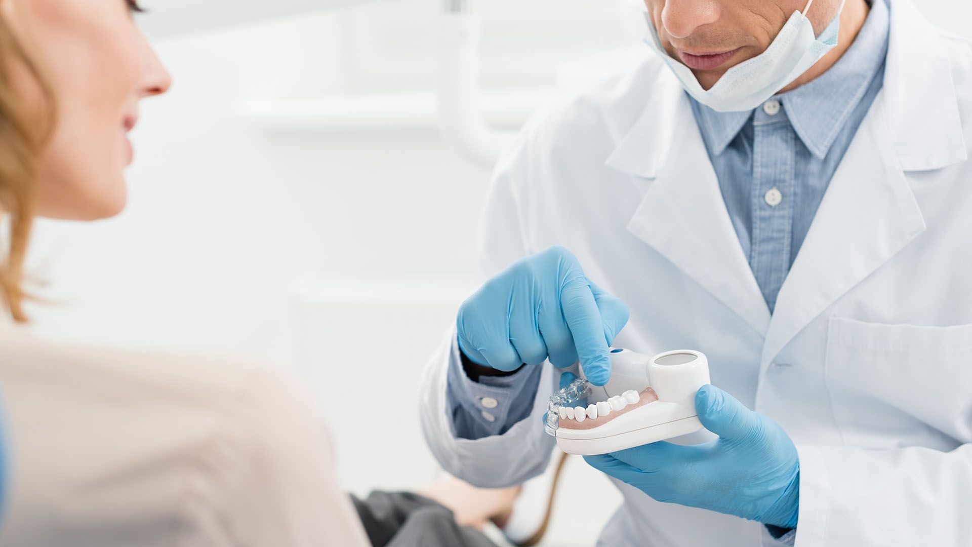 A dentist  points to a a dental model, explaining a procedure to a patient