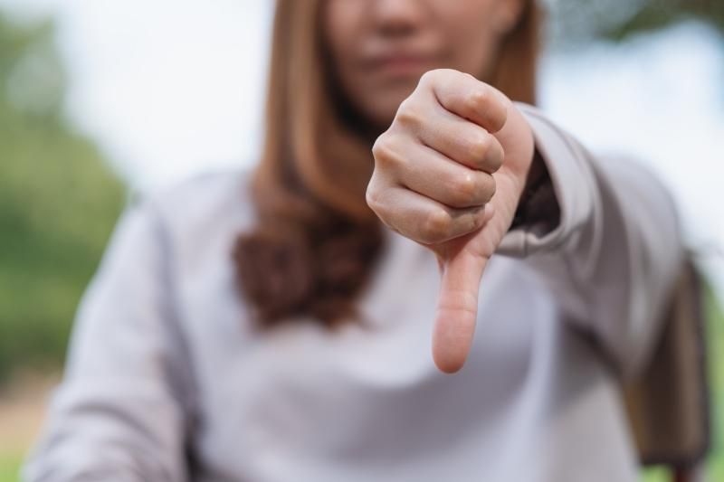 A woman is giving a thumbs-down sign with her hand.