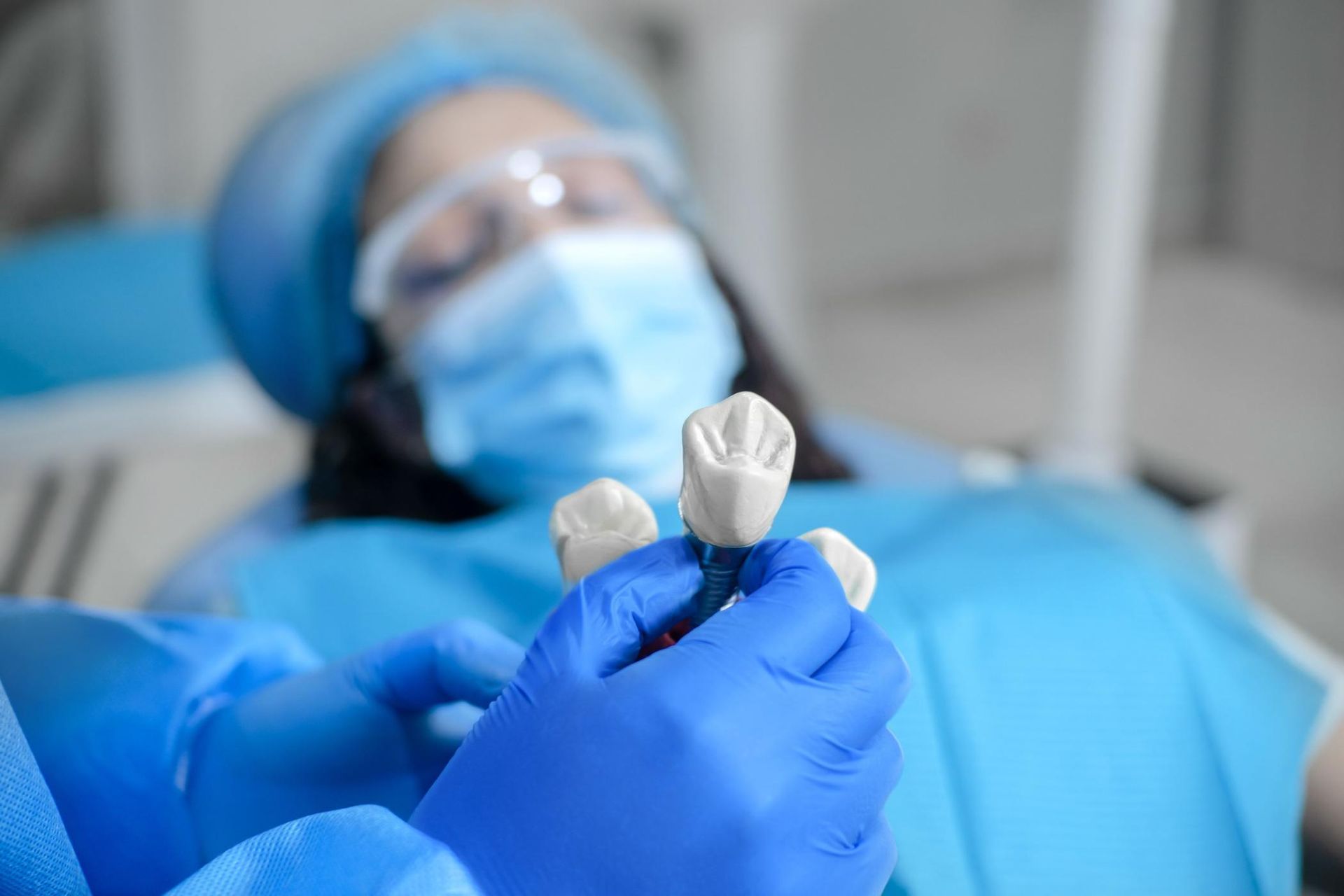 Closeup shot of a dentist showing a dental implant model to a young female patient