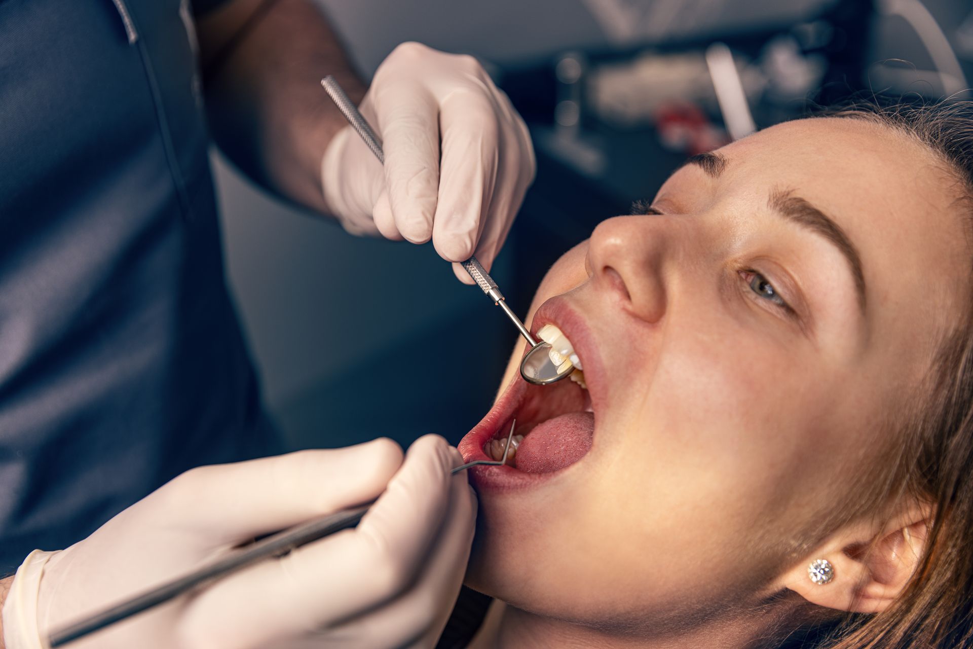 Dentist examining a patient's teeth with dental tools in a dental office.