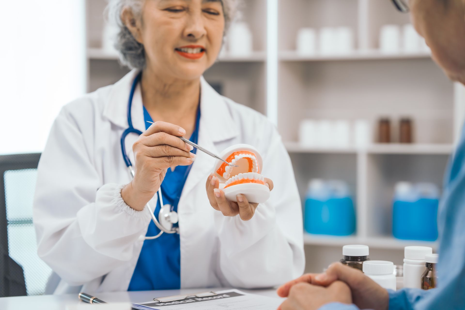 Doctor demonstrating a dental model during a consultation in a clinic with a patient nearby