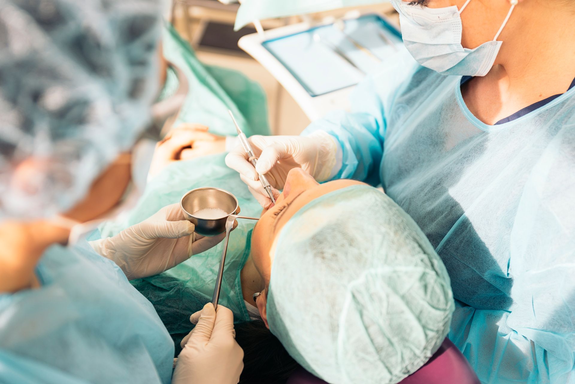 Surgeons operating on a patient in a hospital setting. They are wearing scrubs and masks.