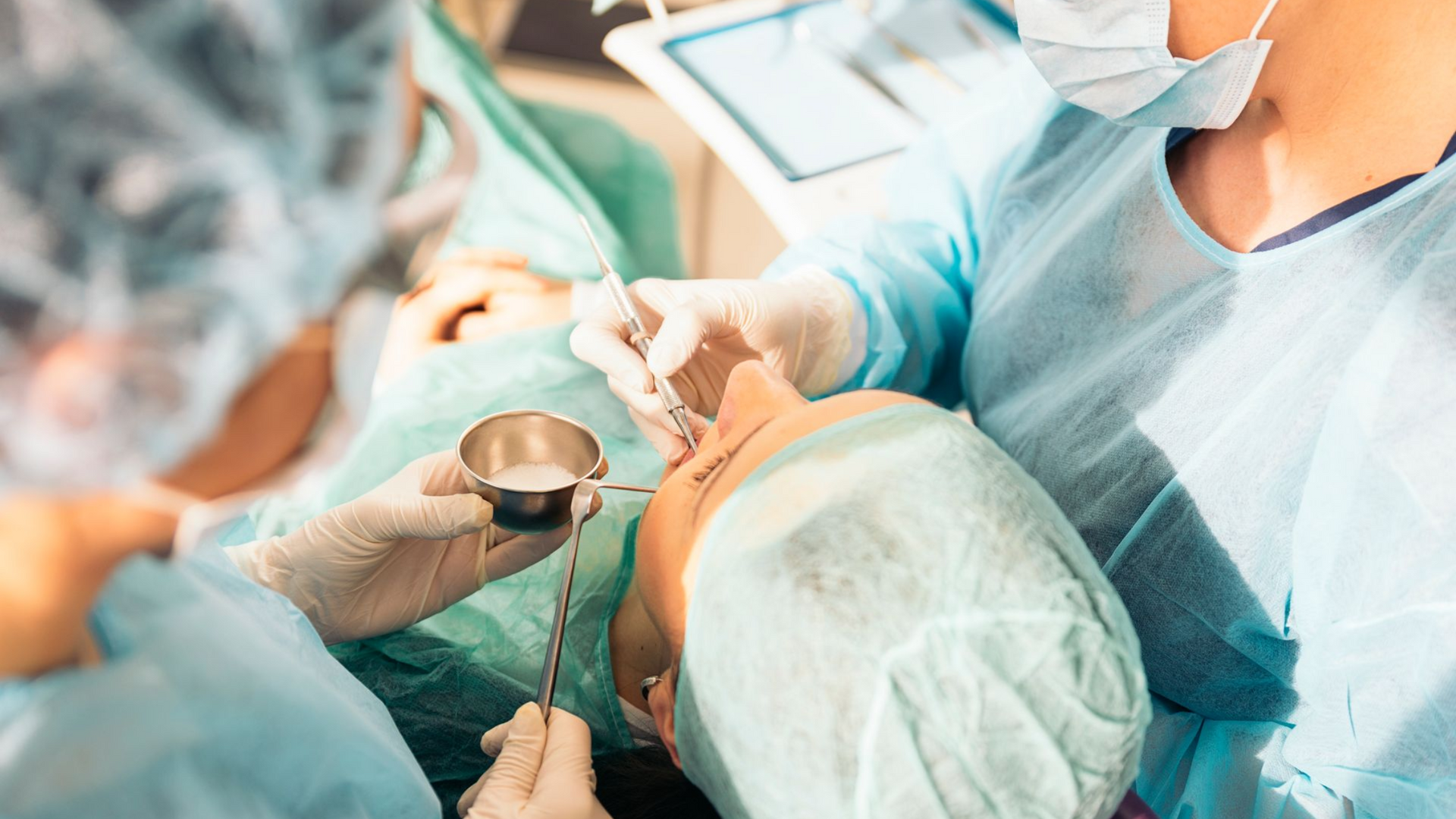 Surgeons performing an operation on a patient lying down. Focus on face and instruments.