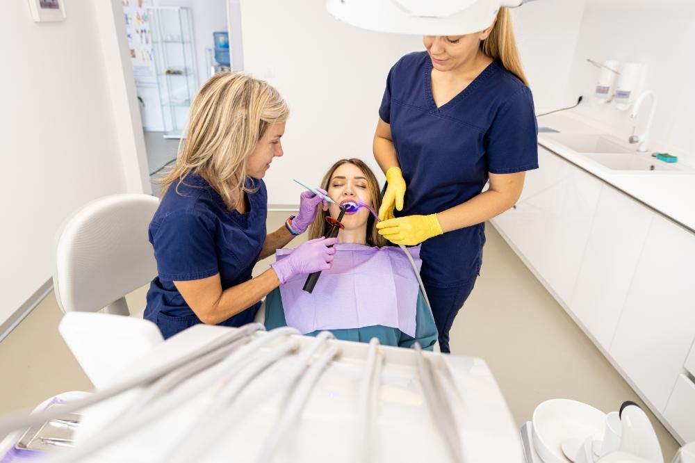 Two female dentists are examining a patient 's teeth in a dental office.