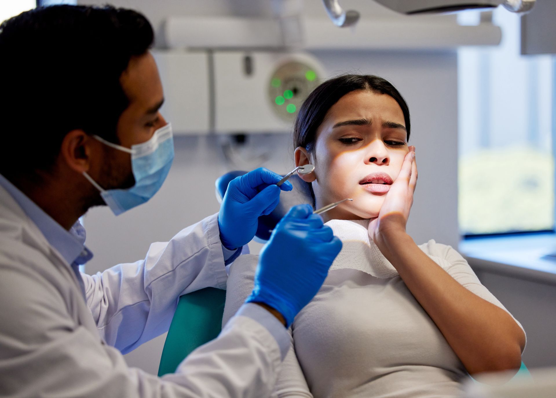 Clinician in blue gloves examining a patient’s neck in a medical office