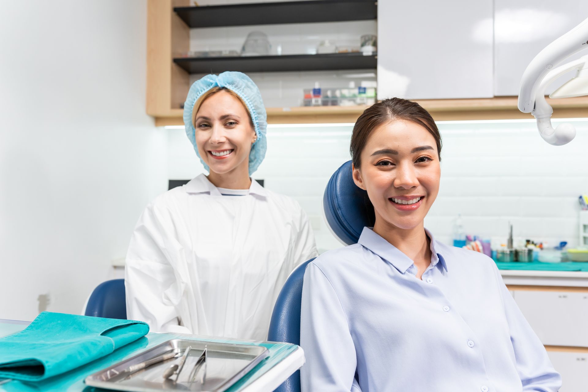 Dentist and patient smiling at the camera in a dental office.