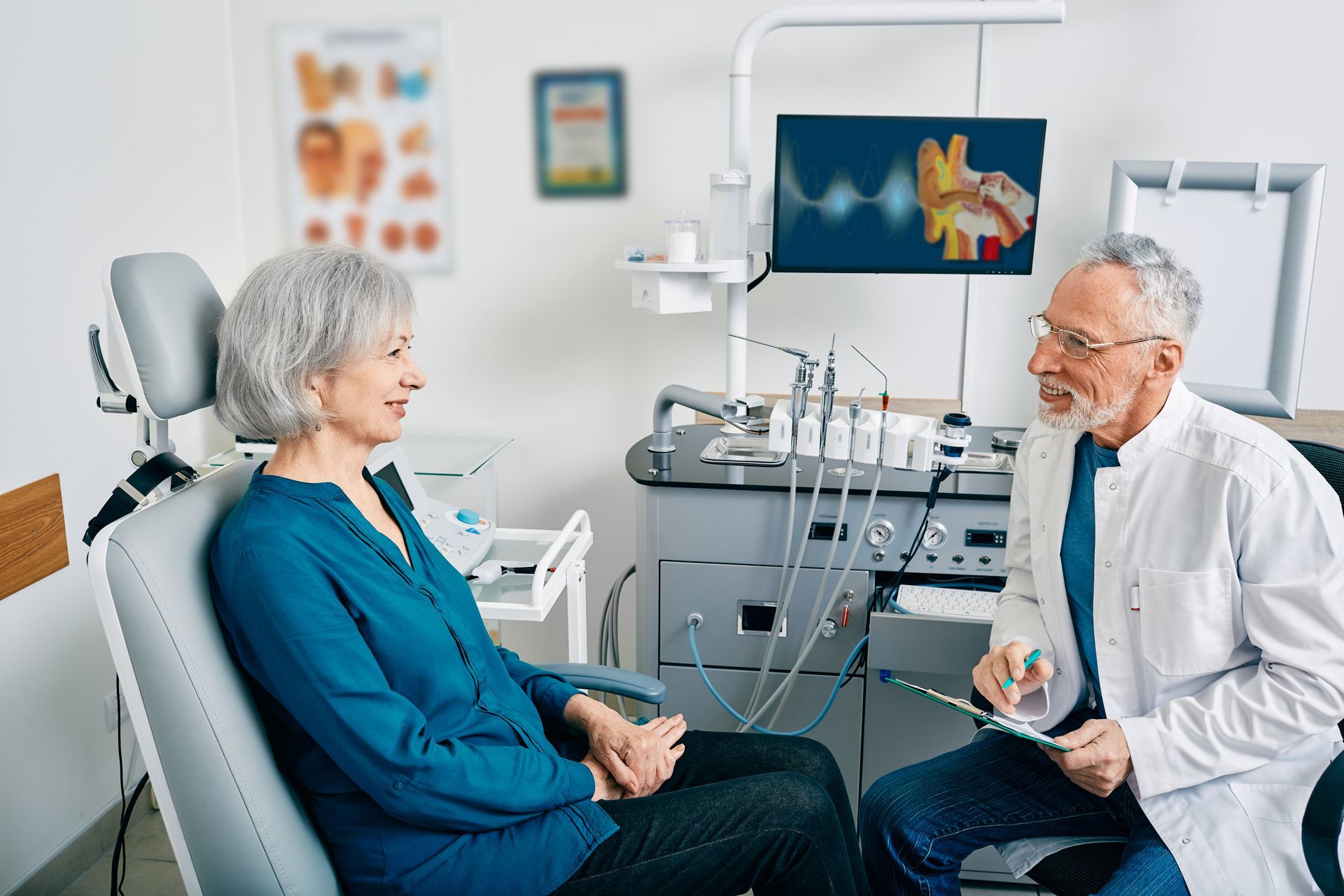 A dentist talking to a patient seated in a dental chair in a dental office.